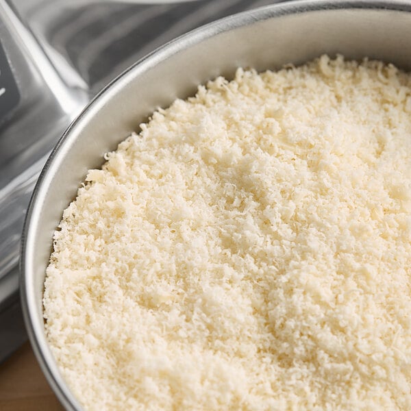 An Estella electric hard cheese grater shredding white cheese into a bowl.