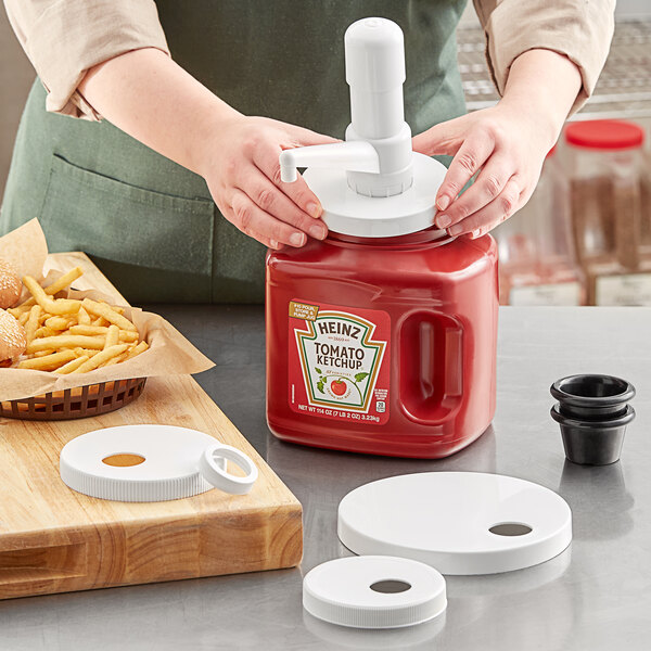 A person using a red Choice condiment pump on a red container of ketchup.