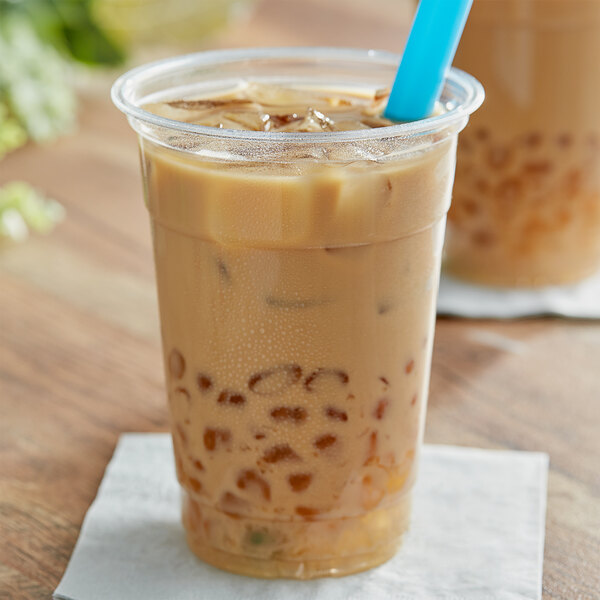 A plastic cup of iced coffee with brown liquid, ice, and a blue straw.