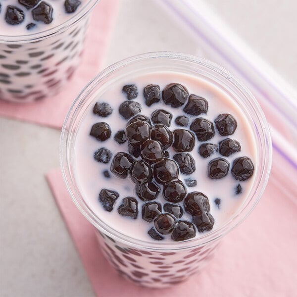 A glass of Fanale tapioca bubble tea with black balls and a straw.