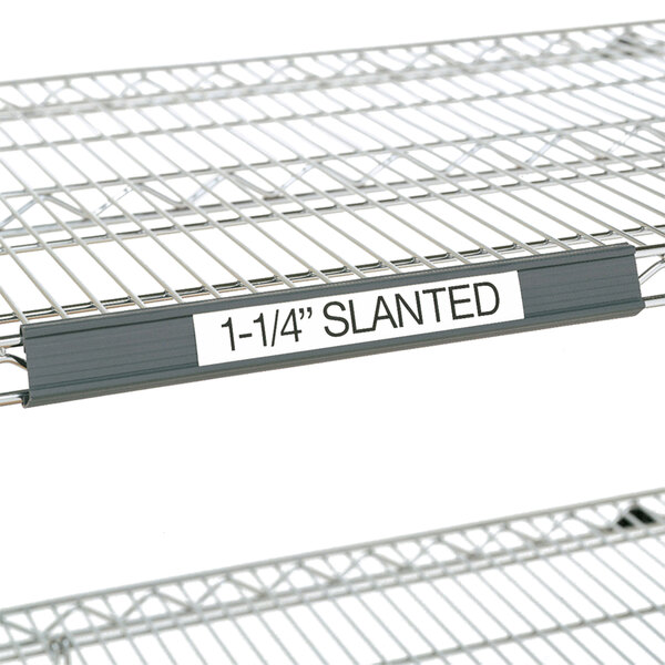 A gray Metro plastic label holder on a slanted shelf.