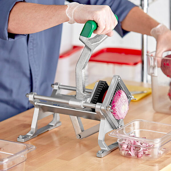 A person using a Garde table mount vegetable dicer to peel a vegetable.