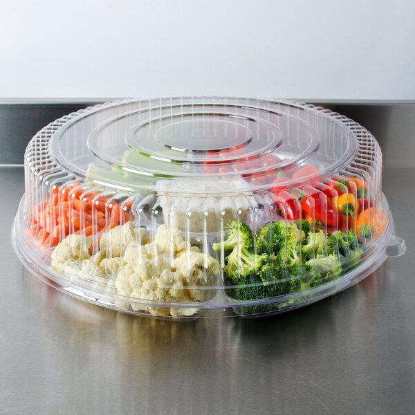 A Fineline clear plastic round high dome lid on a plastic container with broccoli inside.