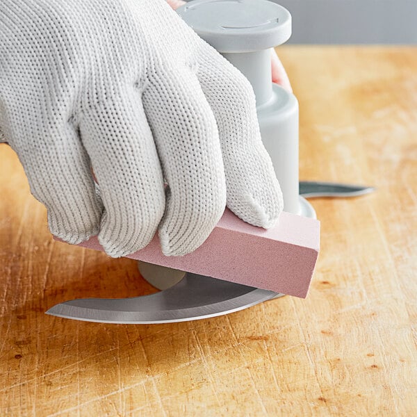 A person using a white gloved hand to hone a knife on a counter.