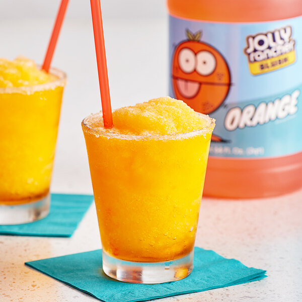 A glass of orange Jolly Rancher slushy with a straw.