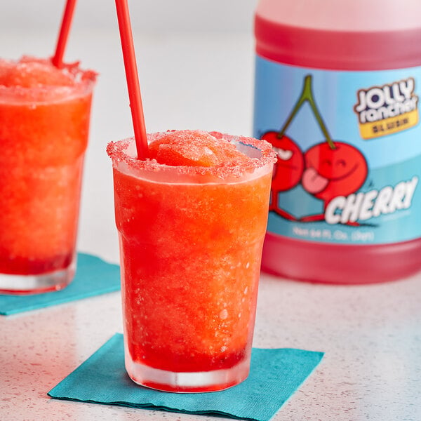 Two glasses of Jolly Rancher cherry slushy with straws on a table.