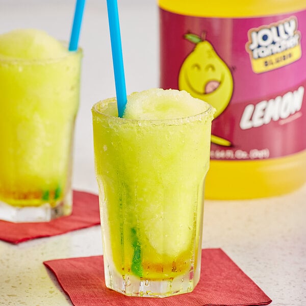 A pair of glasses of yellow Jolly Rancher lemon slushies with straws.
