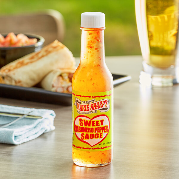 A bottle of Marie Sharp's sweet habanero hot sauce on a table.