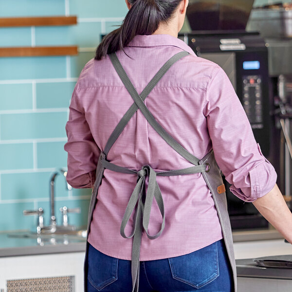 A woman wearing a pebble cross-back apron with Acopa Hazleton straps.