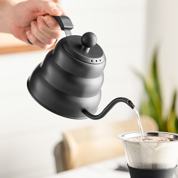 A hand pouring water into an Acopa matte black gooseneck kettle.