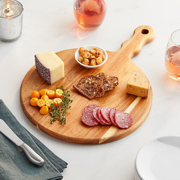 An Acopa acacia wood serving board with cheese, meat, and wine on it.