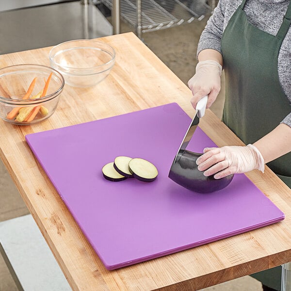 A woman cutting eggplant on a purple Choice cutting board.