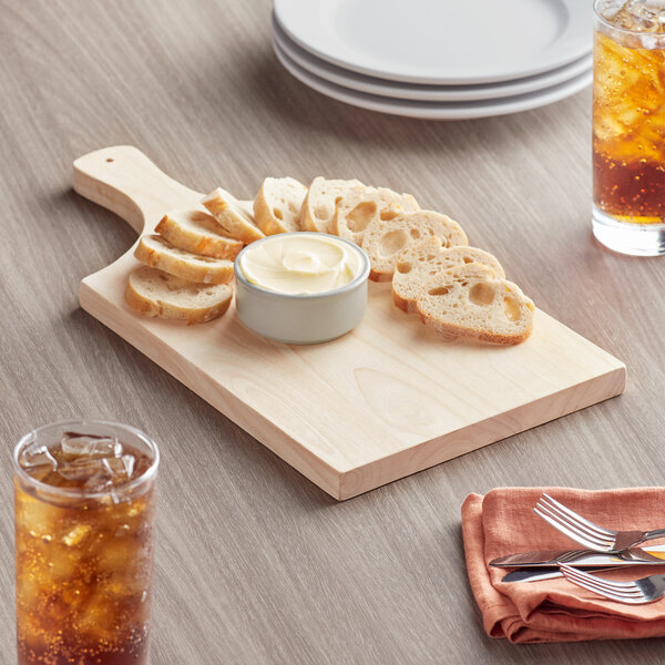 A wooden board with a bowl of bread and a bowl of cream on it.