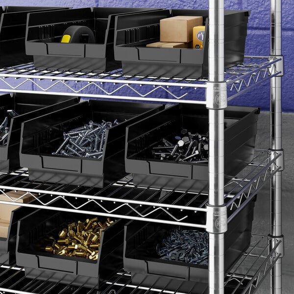 Several black plastic bins are organized on metal wire shelving, each containing various hardware items such as screws, bolts, and small boxes.