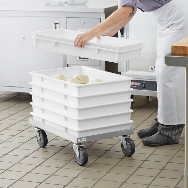 A woman using a white Baker's Mark dough proofing tray to carry food.