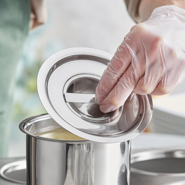 A person in gloves putting a Choice stainless steel bain marie cover on a silver container.