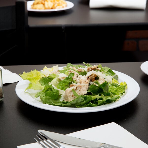 A white Thunder Group Nustone melamine plate with salad, chicken, and lettuce.