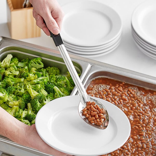 A person using a Choice stainless steel basting spoon with a black handle to serve beans onto a plate.