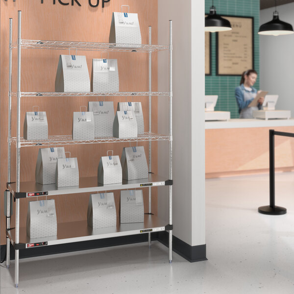 A Metro stainless steel takeout station with heated and chrome shelves holding bags.