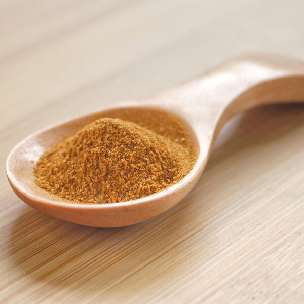 A spoonful of Organic Rosehip Powder on a wooden table.