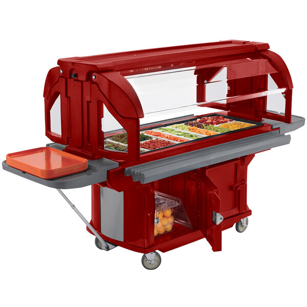 A red Cambro food cart with a tray of food on a table.