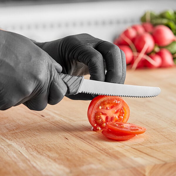 A person using a Schraf serrated utility knife to cut a tomato.