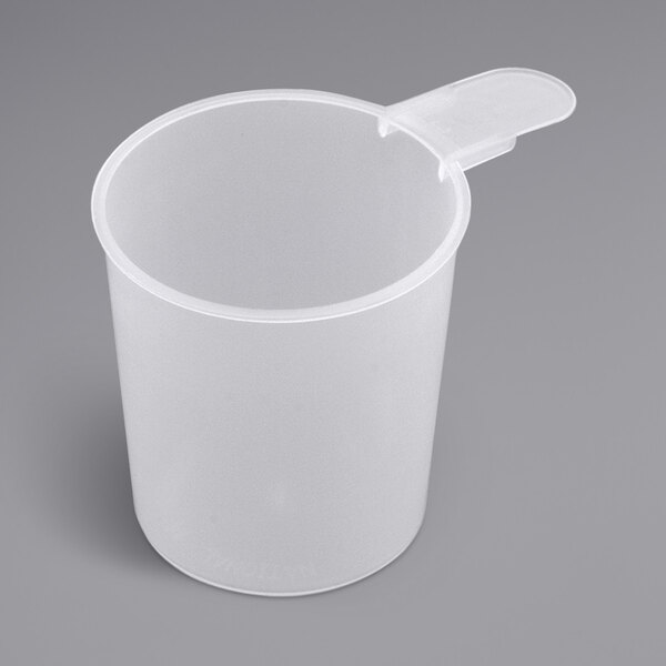 A clear plastic container with a white cylinder on a gray surface and a 7 oz. polypropylene scoop with a short handle.