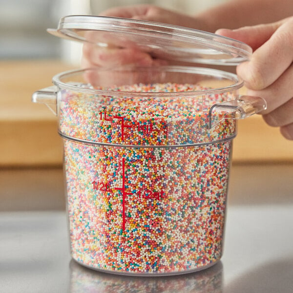 A person pouring colorful sprinkles into a clear plastic Choice food storage container.