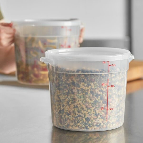 A woman using a Choice translucent plastic food storage container with a lid to store a mixture of beans.