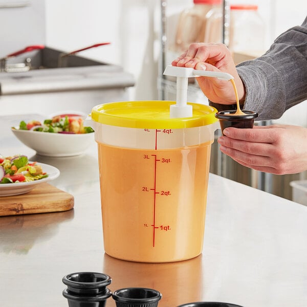 A hand using a Choice condiment pump to pour yellow liquid into a container with a yellow lid.