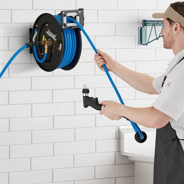 A man holding a Regency hose reel with a hose spraying water.