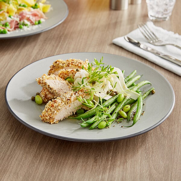 An Acopa Apollo matte grey and black melamine plate with chicken and green beans on a table.
