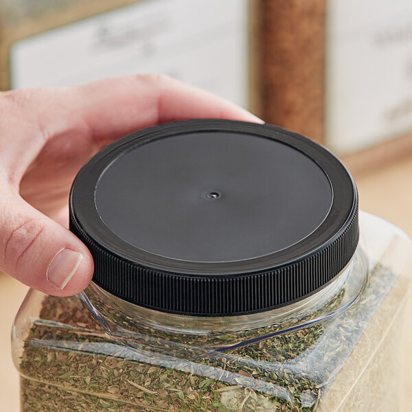 A hand holding a plastic container with a black 89/400 unlined ribbed plastic cap.