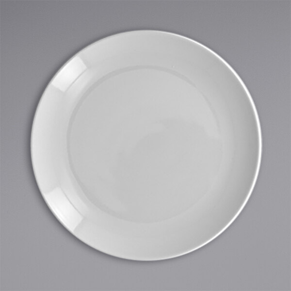A close-up of a white RAK Porcelain flat coupe plate with a white rim.