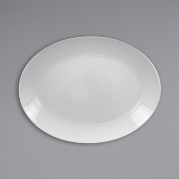 A white RAK Porcelain oval coupe platter with a white rim on a gray surface.
