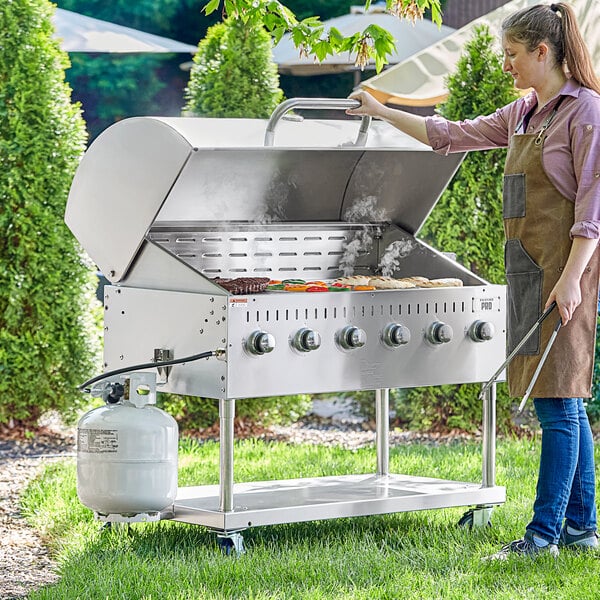 A woman cooking food on a large stainless steel Backyard Pro outdoor grill.
