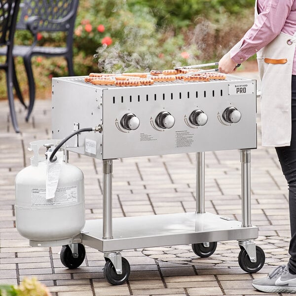 A woman cooking food on a Backyard Pro stainless steel liquid propane grill outdoors.