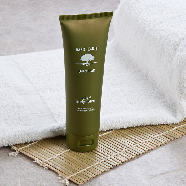 A green tube of Basic Earth Botanicals Refreshing Body Lotion on a white towel.
