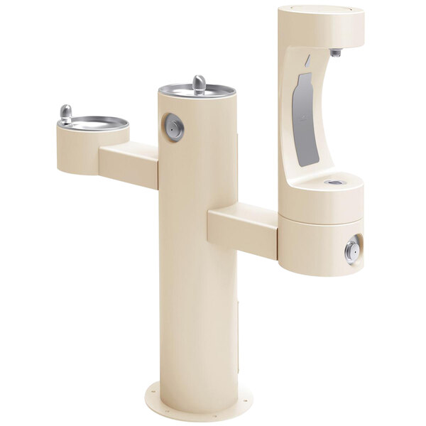 A beige outdoor pedestal drinking fountain with silver faucets.