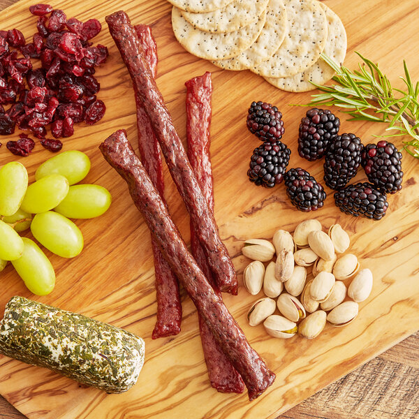 A wood board with Shaffer Venison Farms Pepper Venison Snack Sticks and other snacks.