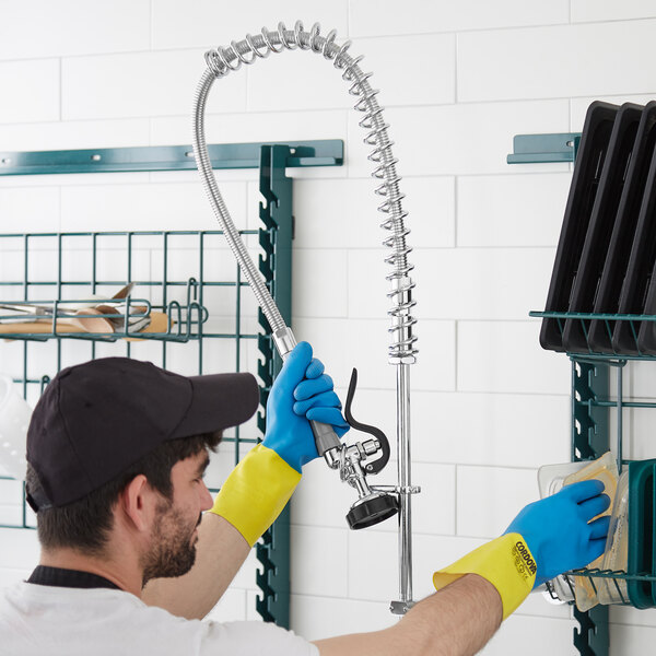 A man in blue gloves holding a 44" pre-rinse hose.