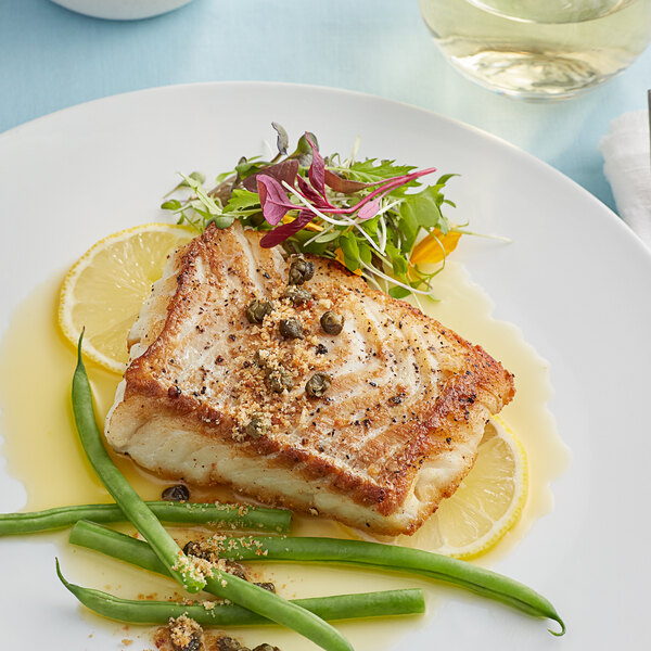 A plate with a Wulf's Icelandic cod loin with lemon and green beans.