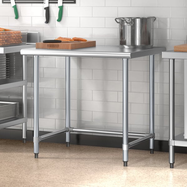 A Steelton stainless steel open base work table in a kitchen with a cutting board and a container on it.