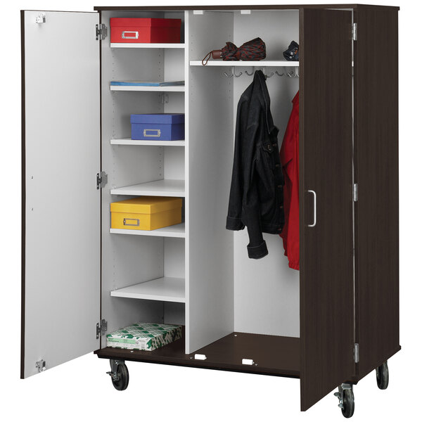 A tall midnight maple storage cart with locking doors and shelves holding clothes and shoes.