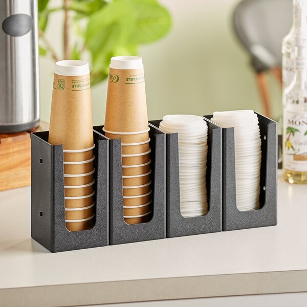 A Choice black countertop cup or lid organizer holding four paper coffee cups.