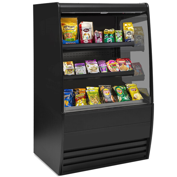 A black Federal Industries non-refrigerated display case with different types of food on shelves.