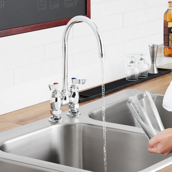 A person using a Waterloo Red "Hot" faucet handle to fill a glass with water over a sink.