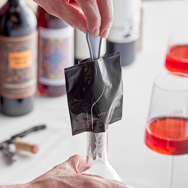 A hand using a Franmara wine preserving insert fork to preserve wine in a bottle.