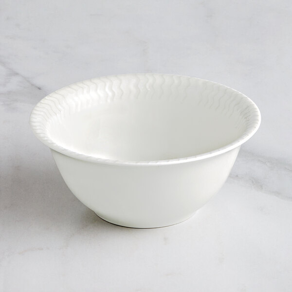 A RAK Porcelain ivory bowl with wavy lines on a marble surface.