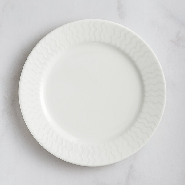 A RAK Porcelain ivory flat plate with wavy lines on the rim.